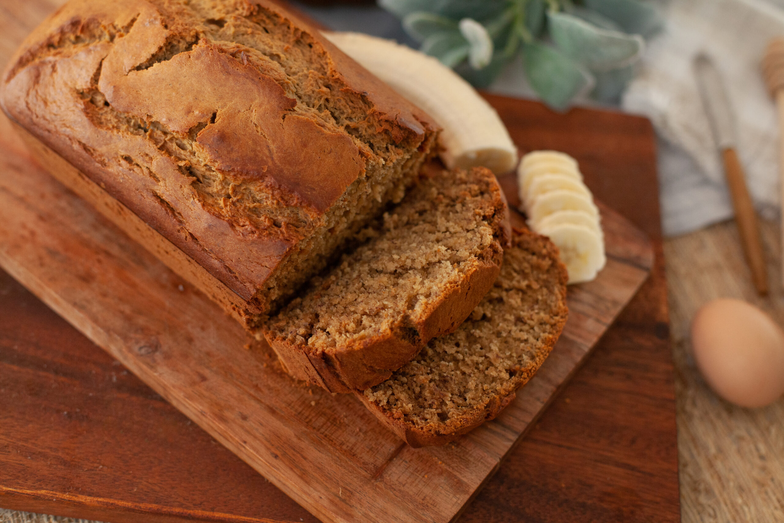 sliced banana bread on a cutting board with banana