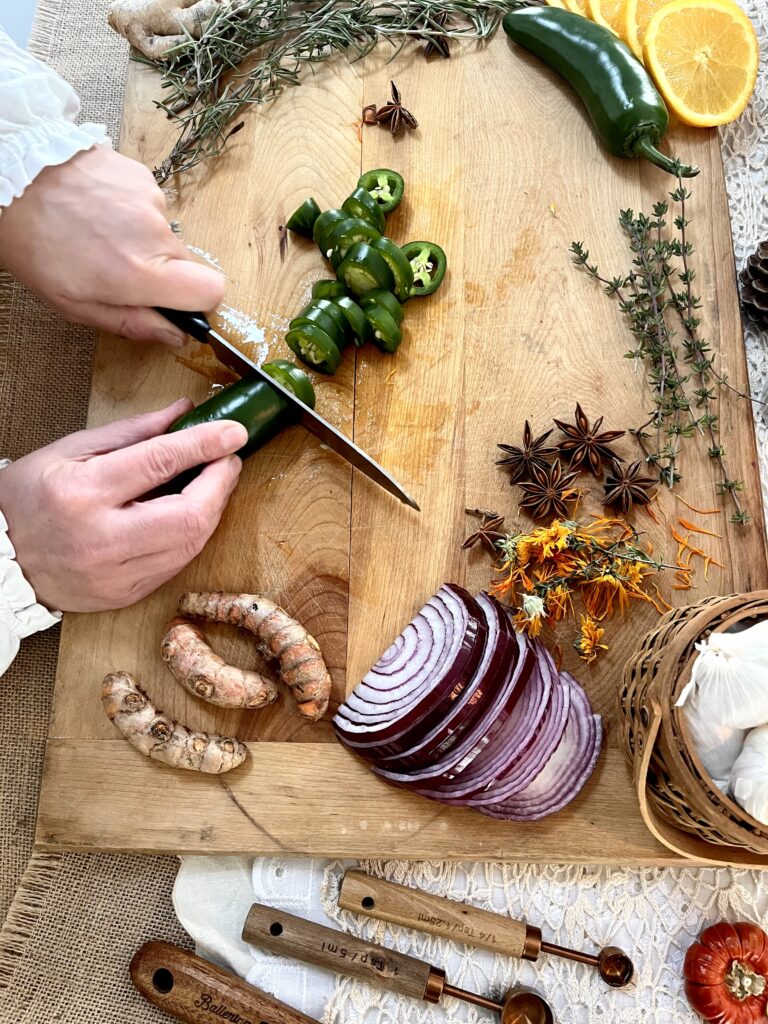 Chopping up ingredients for fire cider on wooden cutting board 