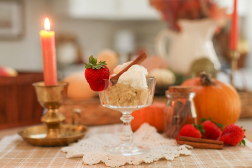 rice pudding in dessert glass by a candle and pumpkin